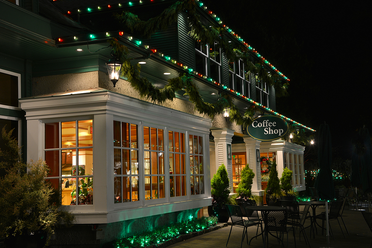 Vue rapprochée du bâtiment et de l'enseigne du Coffee Shop, décorés de lumières de Noël et de branches de cèdre.