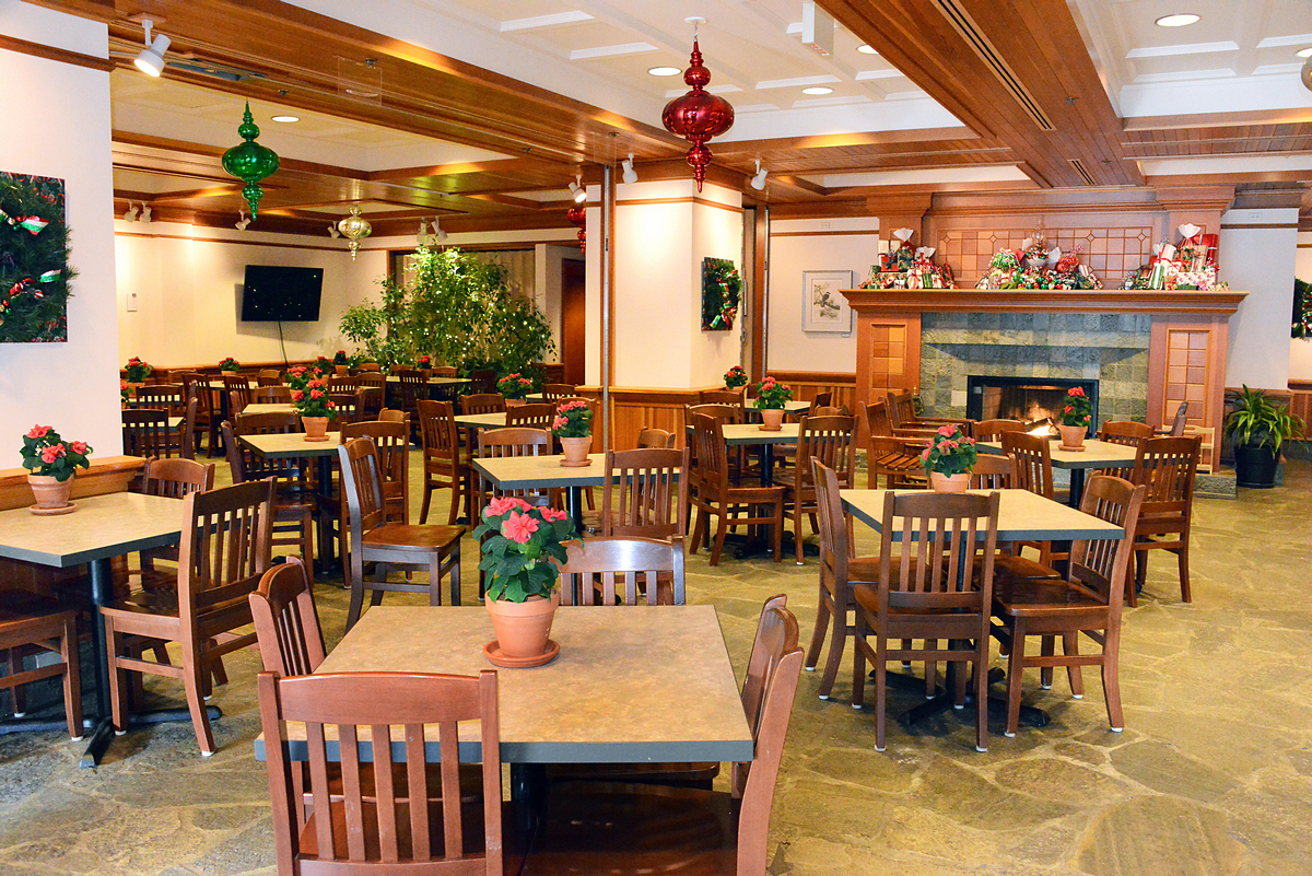 Vue intérieure de tables vides dans le Coffee Shop, décoré pour la saison de Noël avec des poinsettias, des orbes de Noël géantes et des cadeaux.